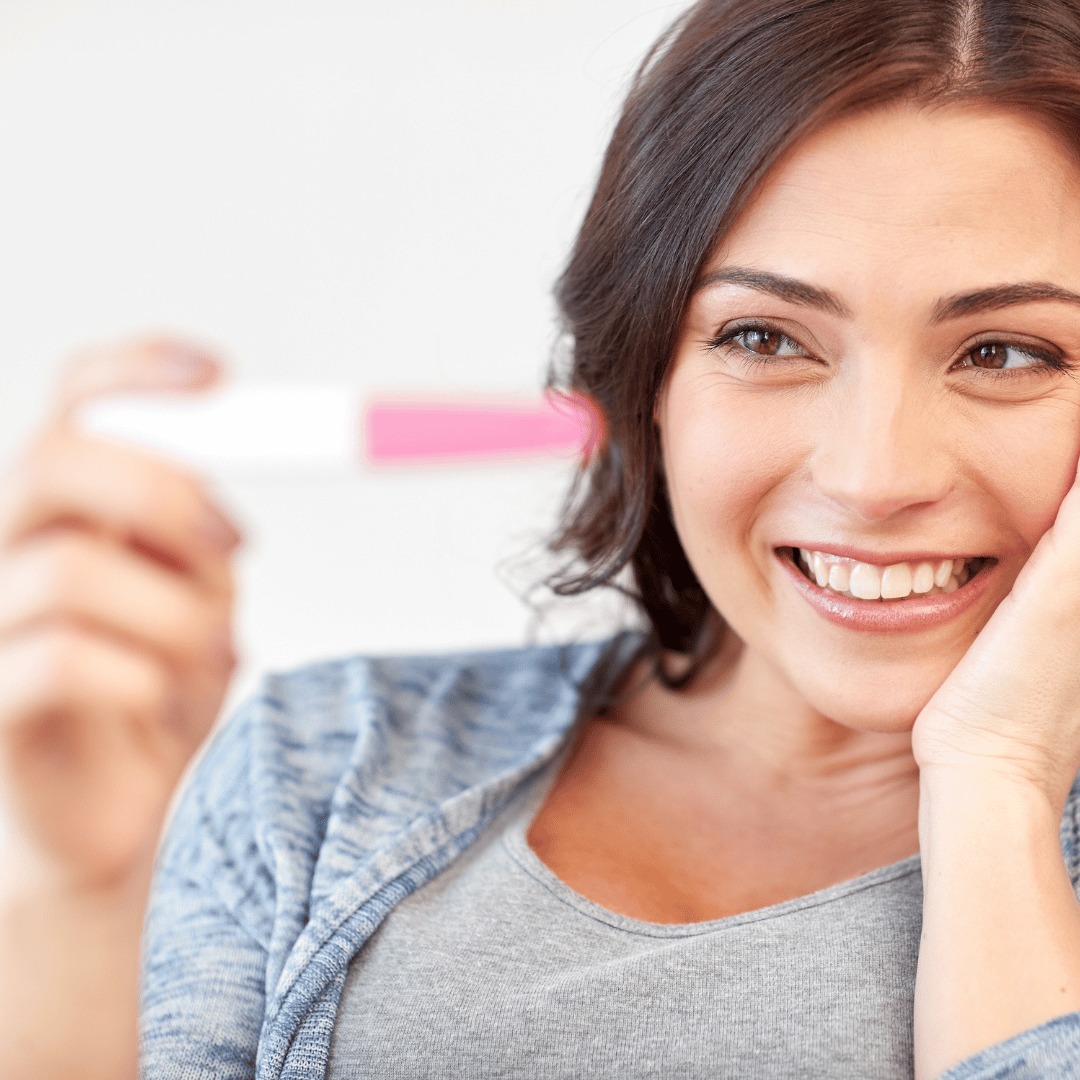 A happy smiling woman looking at her positive ovulation or pregnancy test