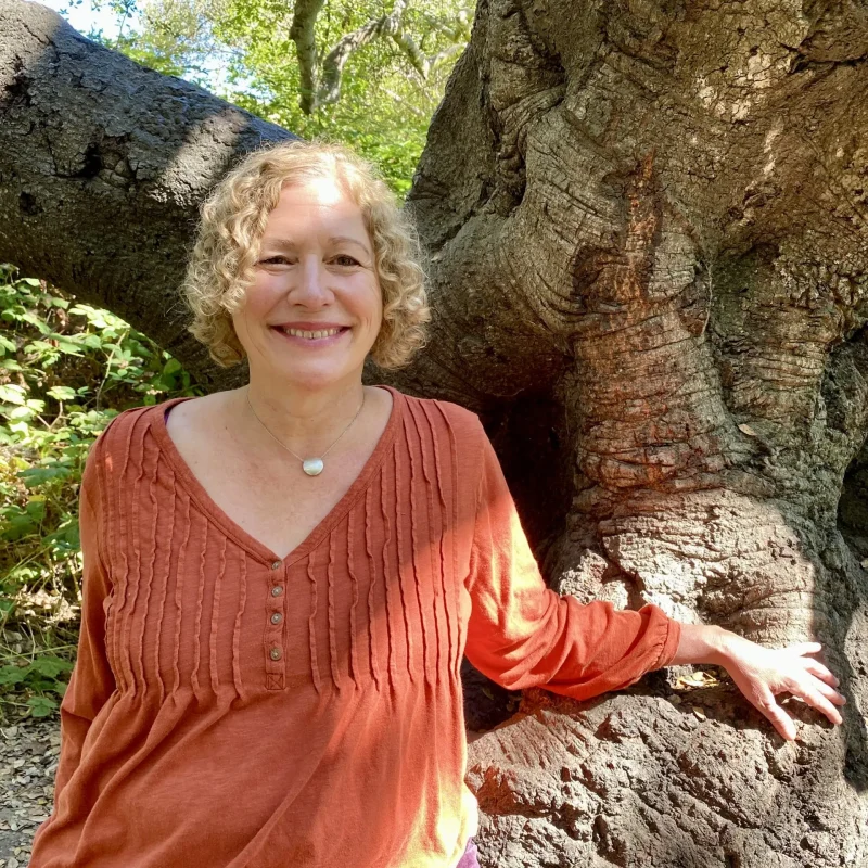 Laura stands next to a tree.